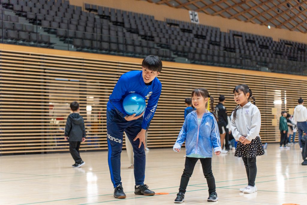 四日市アリーナでTSV1973四日市のサッカー選手が子どもにシュート体験を指導している様子｜MiRAI主催のスポーツイベント