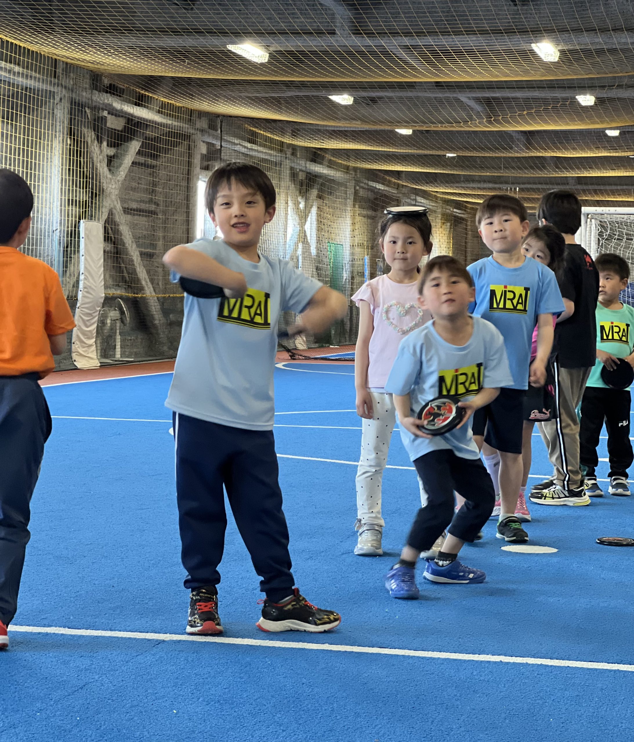 四日市市の体育スクールMiRAIでフリスビーを正確に投げる練習に挑戦する子どもの様子