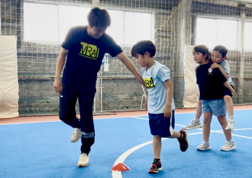 四日市市の体育スクールMiRAIで、けいた先生と子どもたちが走り高跳びに初めて挑戦する様子