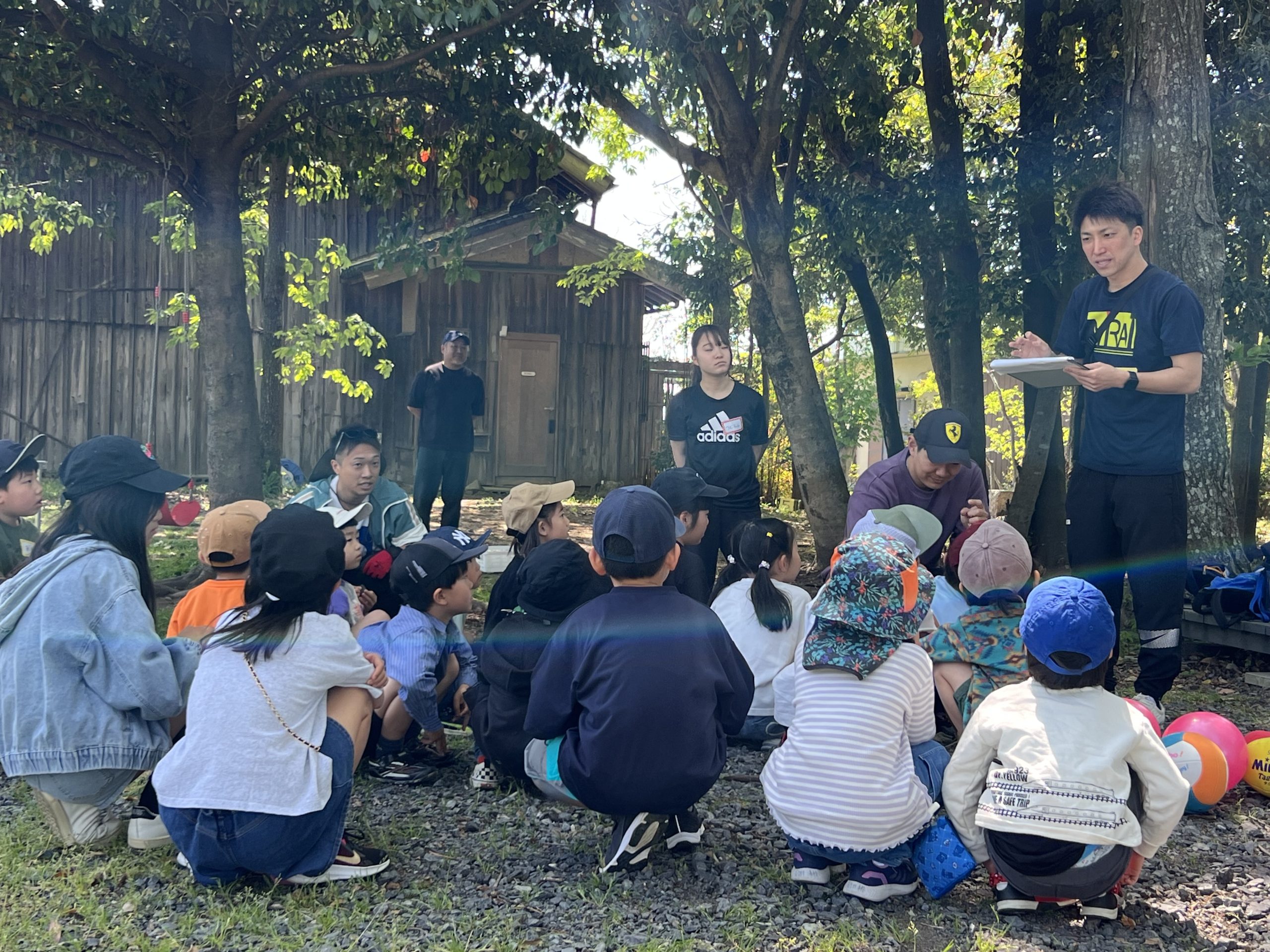 MiRAIヒミツ基地デイキャンプの開会式で、けいた先生とスタッフが自己紹介と一日の流れを説明する様子（四日市・菰野町）