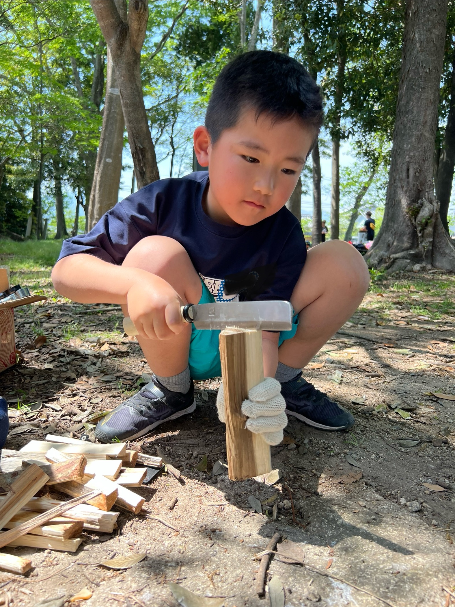 MiRAIヒミツ基地デイキャンプで、初めての薪割りに真剣な表情で取り組む男の子の様子（三重県菰野町）