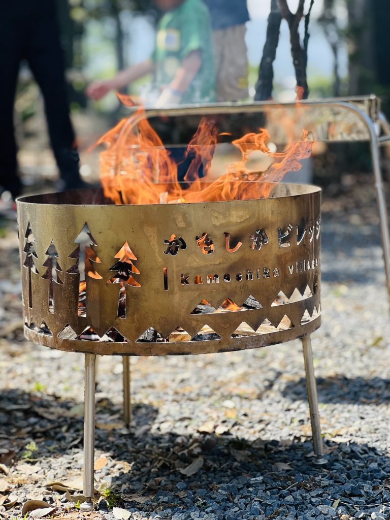 三重県菰野町のかもしかビレッジに設置された焚き火暖炉と、その中で燃える炎。MiRAIのヒミツ基地デイキャンプで、子どもたちのやる気や挑戦心を象徴するシーン。