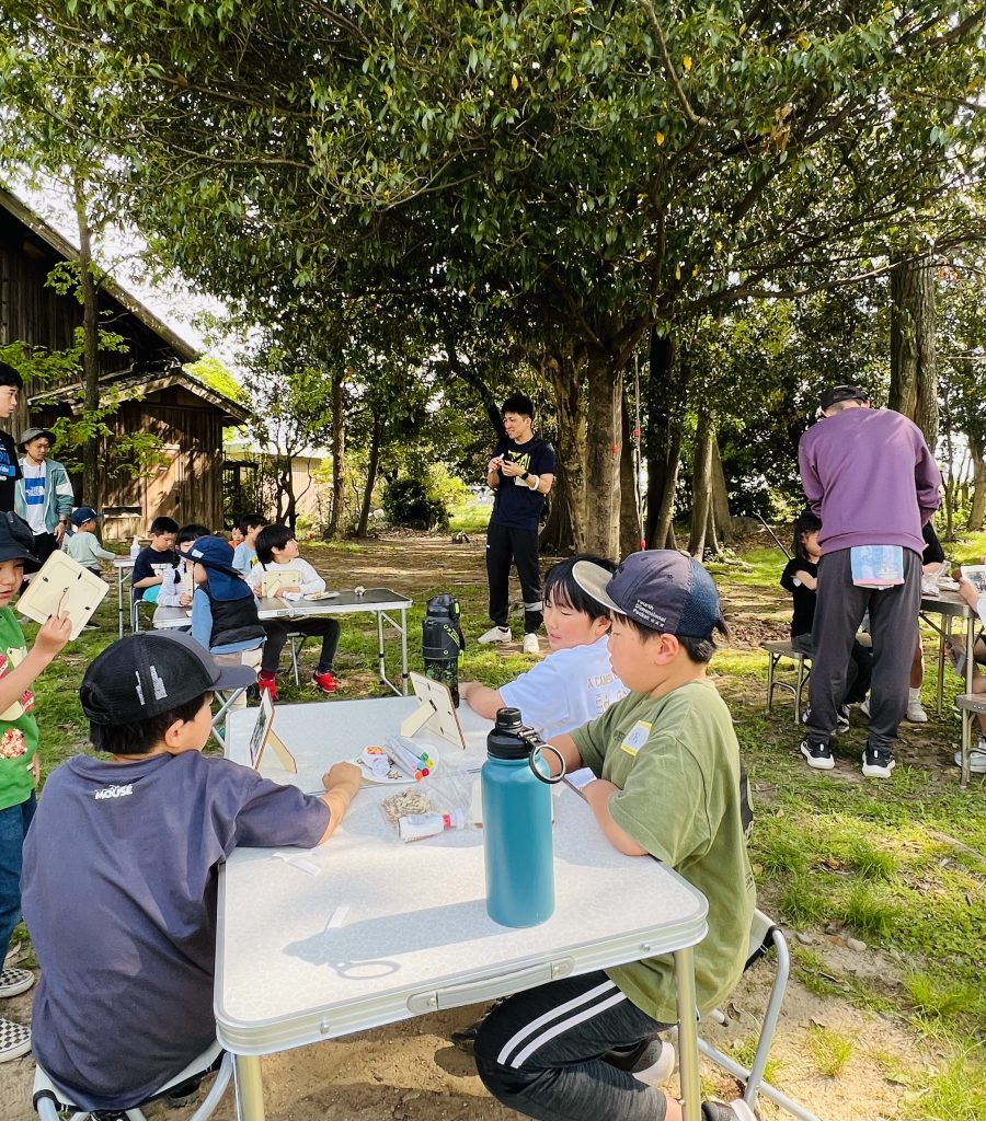 MiRAIヒミツ基地デイキャンプで、子どもたちが真剣にフォトフレームを創作し、思い出の集合写真を貼って完成させている様子。四日市・菰野町を拠点とした子ども向け体験型習い事の一場面。