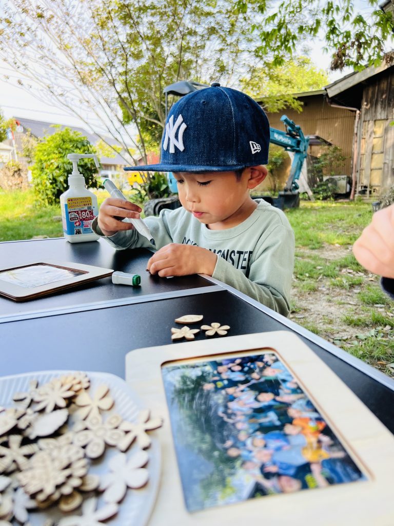 MiRAIヒミツ基地デイキャンプで、子どもたちが真剣にフォトフレームを創作し、思い出の集合写真を貼って完成させている様子。四日市・菰野町を拠点とした子ども向け体験型習い事の一場面。