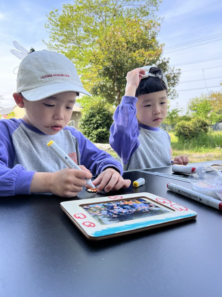 MiRAIヒミツ基地デイキャンプで、子どもたちが真剣にフォトフレームを創作し、思い出の集合写真を貼って完成させている様子。四日市・菰野町を拠点とした子ども向け体験型習い事の一場面。