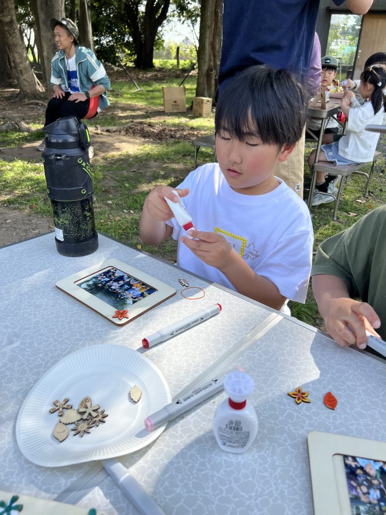 MiRAIヒミツ基地デイキャンプで、子どもたちが真剣にフォトフレームを創作し、思い出の集合写真を貼って完成させている様子。四日市・菰野町を拠点とした子ども向け体験型習い事の一場面。