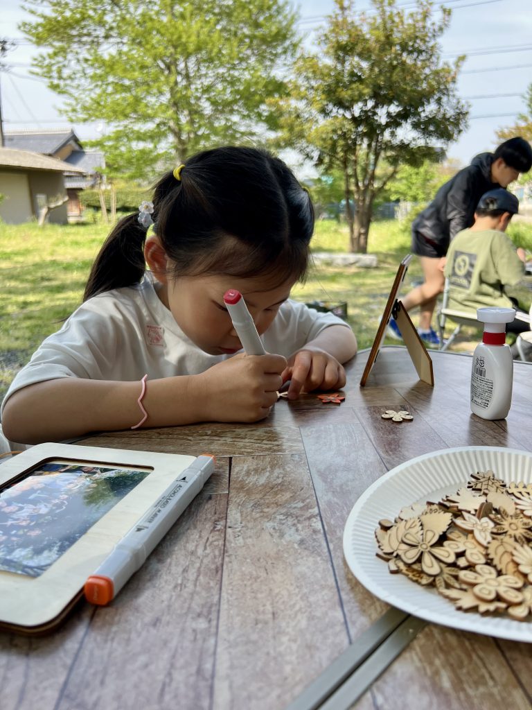 MiRAIヒミツ基地デイキャンプで、子どもたちが真剣にフォトフレームを創作し、思い出の集合写真を貼って完成させている様子。四日市・菰野町を拠点とした子ども向け体験型習い事の一場面。