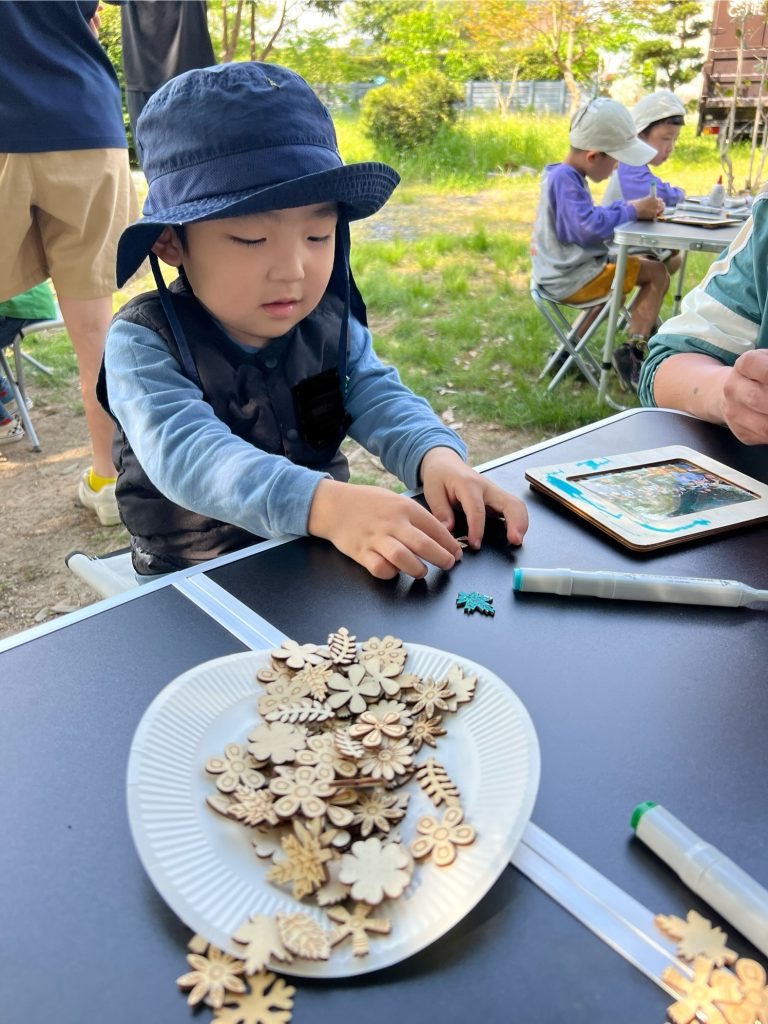 MiRAIヒミツ基地デイキャンプで、子どもたちが真剣にフォトフレームを創作し、思い出の集合写真を貼って完成させている様子。四日市・菰野町を拠点とした子ども向け体験型習い事の一場面。