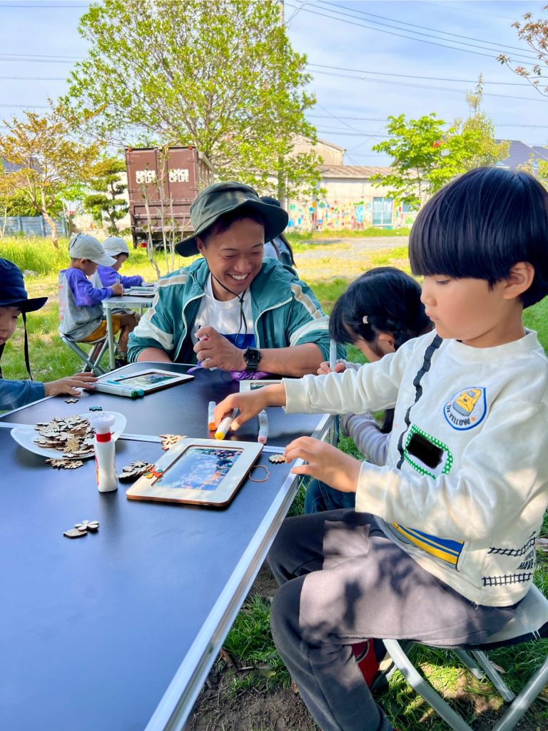 MiRAIヒミツ基地デイキャンプで、子どもたちが真剣にフォトフレームを創作し、思い出の集合写真を貼って完成させている様子。四日市・菰野町を拠点とした子ども向け体験型習い事の一場面。
