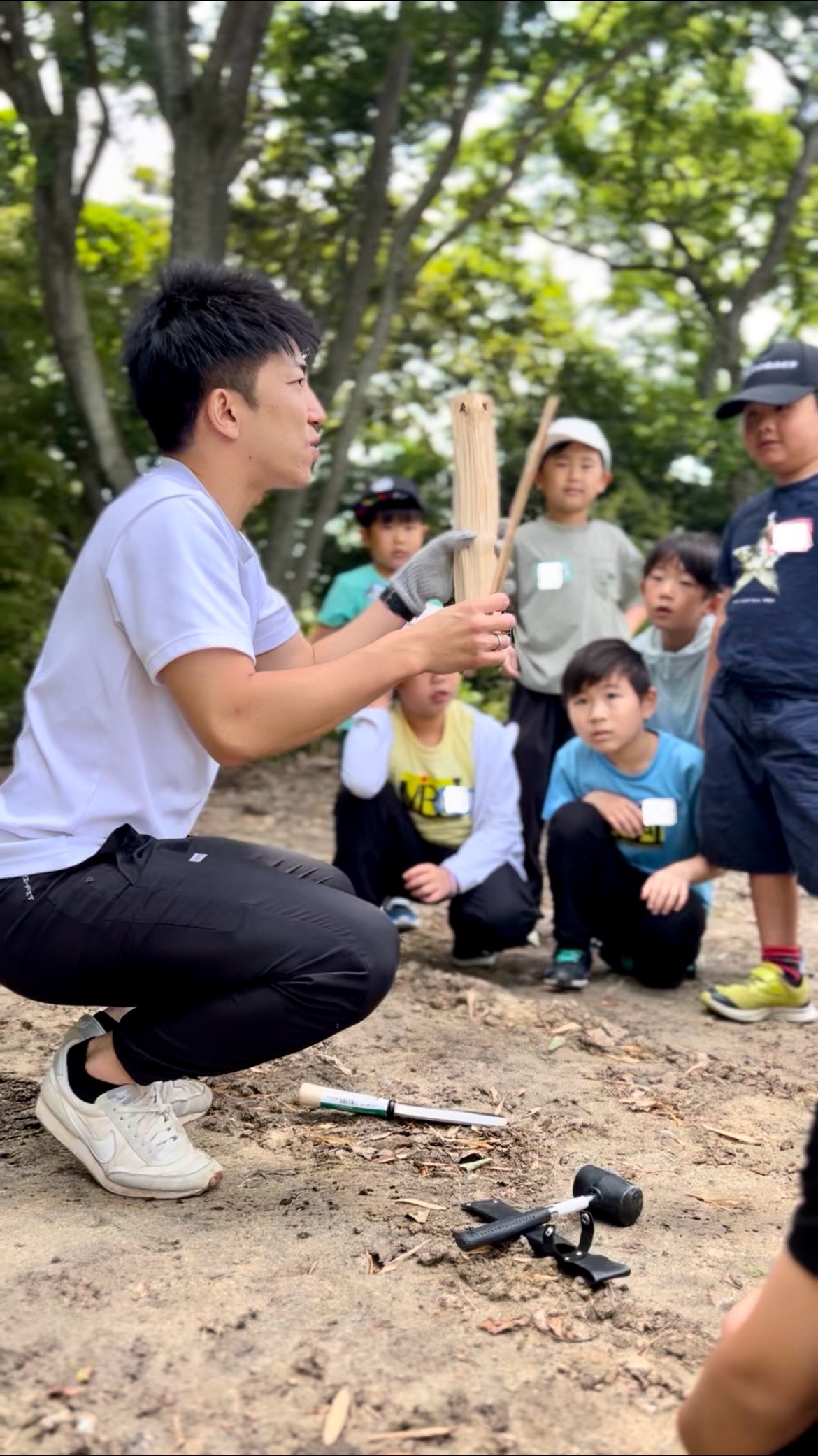 四日市のMiRAI体験スクールで薪割りを指導するけいた先生と子どもたち
