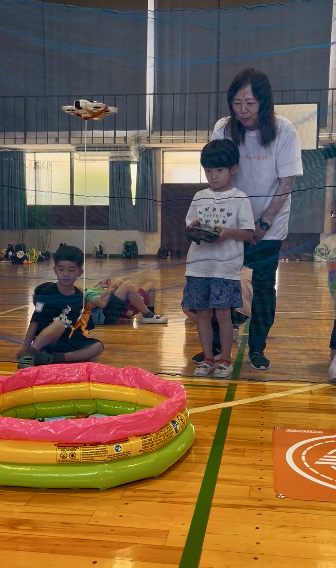 MiRAIドローン体験イベントで恐竜釣りに挑戦する小学生の男の子が、真剣な表情でドローンを操作している様子（三重県四日市市）