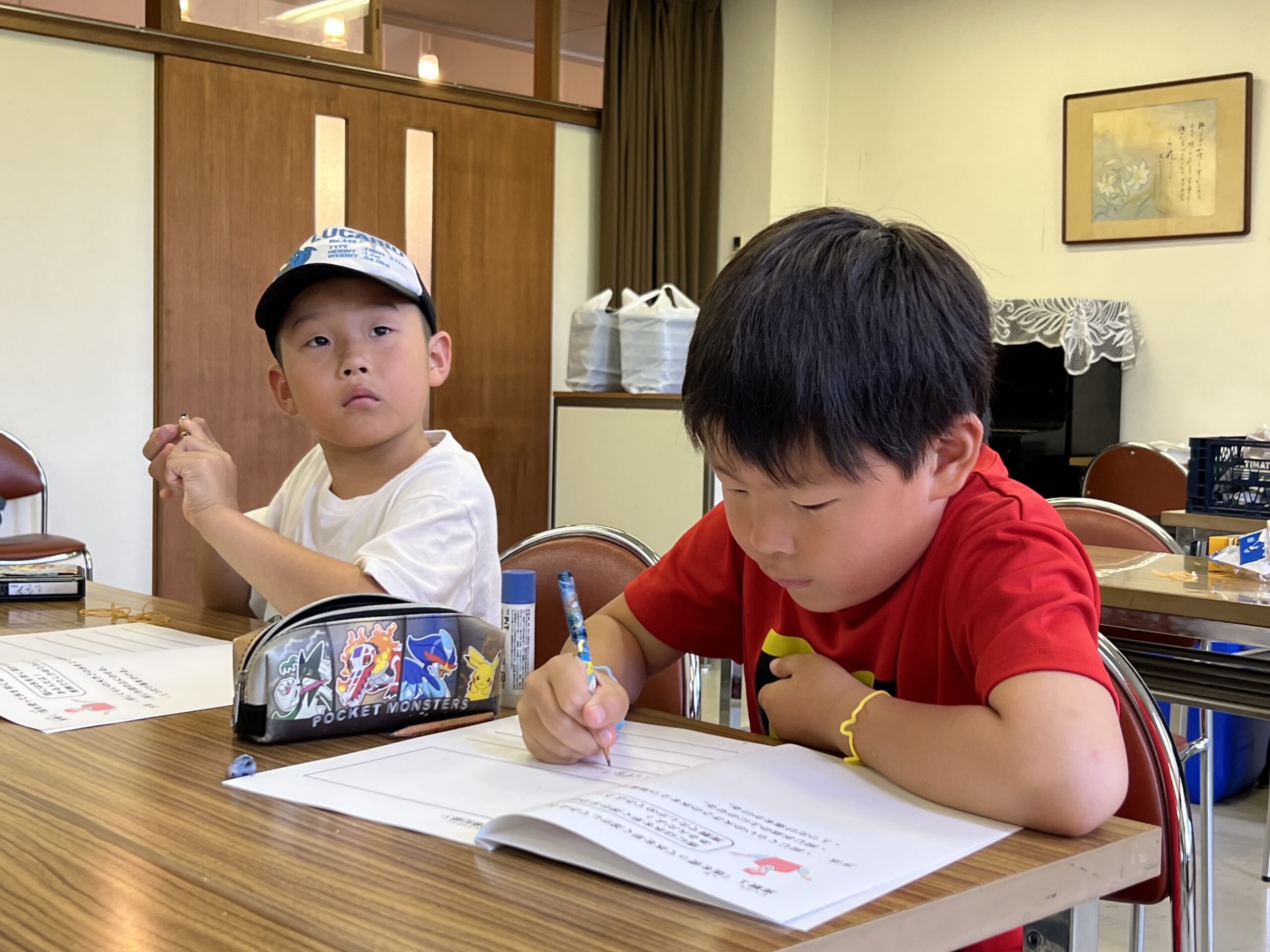 四日市メリノール学院の施設「静修館」の教室で、MiRAIサマスクに参加する子どもたちが机に向かい、夏休みの学習活動に集中して取り組んでいる様子