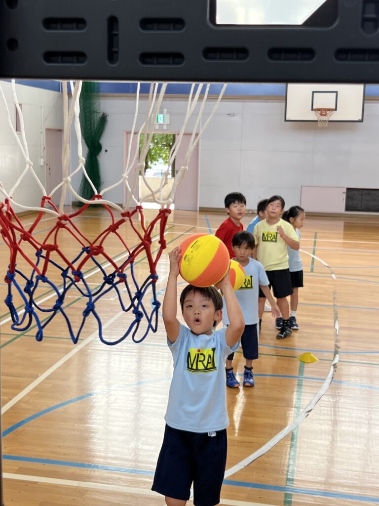 四日市・菰野町エリアの小学生が、総合スポーツスクールMiRAIの体験会でバスケットボールをシュートする瞬間の様子