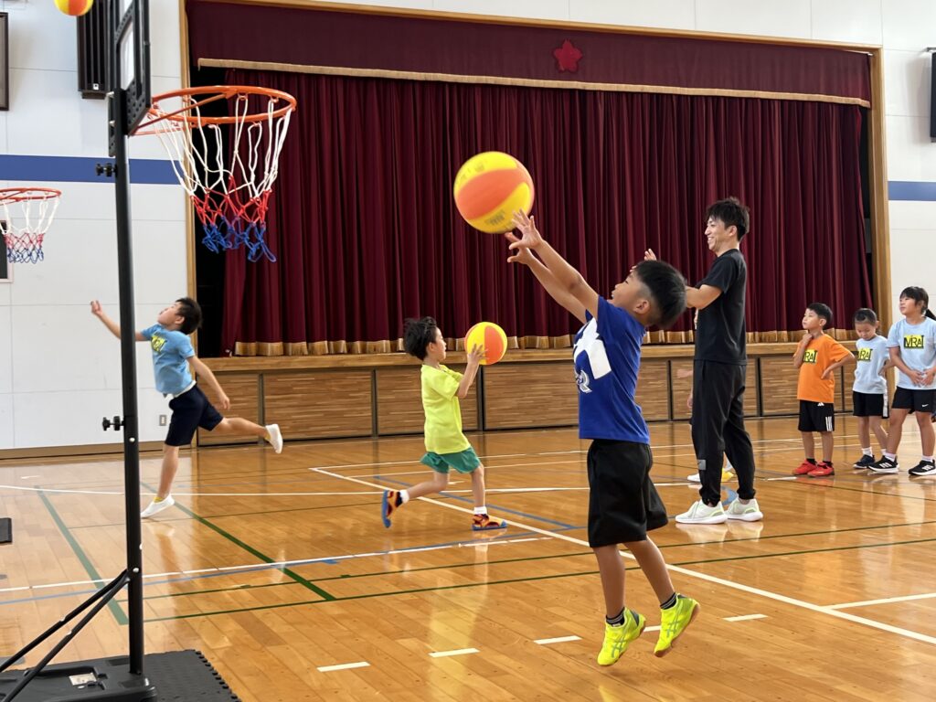 四日市・菰野町エリアの小学生が、総合スポーツスクールMiRAIの体験会でバスケットボールをシュートする瞬間の写真