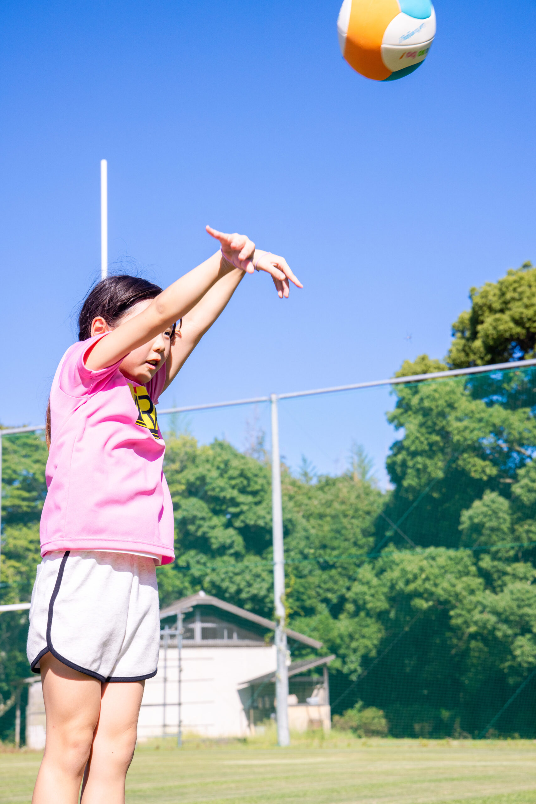 三重県菰野町のスポーツスクールMiRAIで、小学生の女の子がネット型スポーツとしてバレーボールのトスに挑戦している様子
