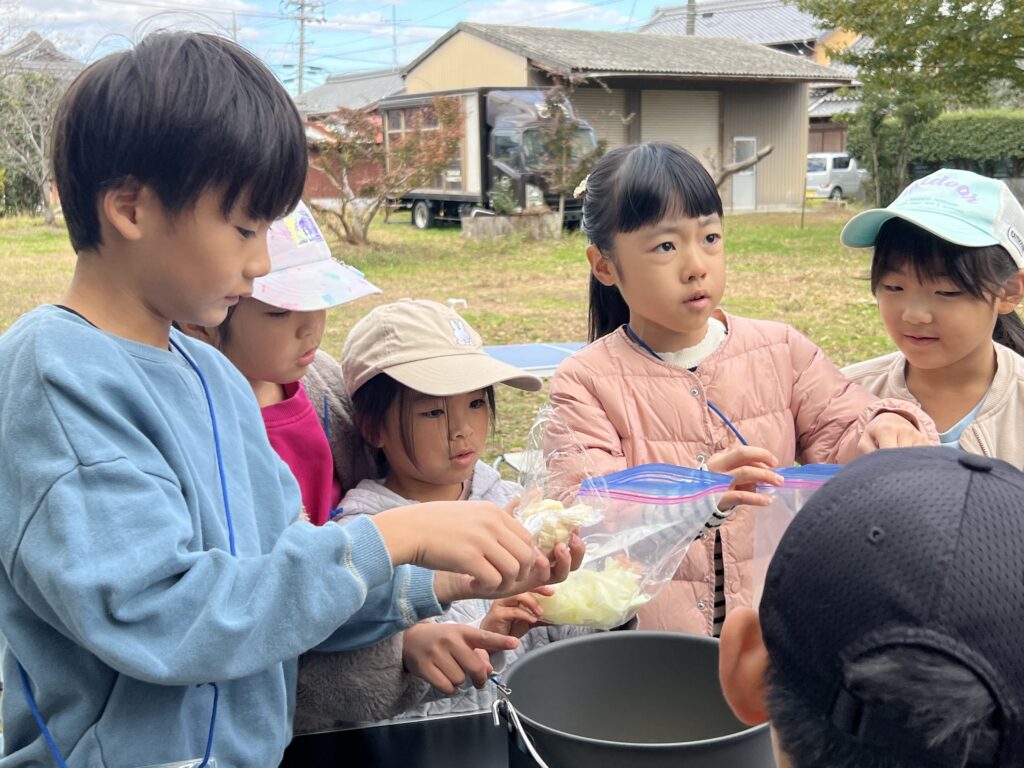 年中〜小6対象】四日市市・菰野町の習い事。総合スポーツスクールMiRAIの野外体験で子どもたちがチームワークを発揮して食事を準備している様子。