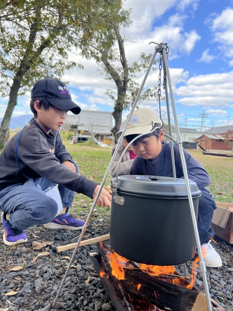 年中〜小6対象】三重県北勢（四日市市・菰野町）のキッズスポーツ。MiRAIのキャンプで、子どもたちが協力して火加減を調整し、問題解決力を高めている様子。