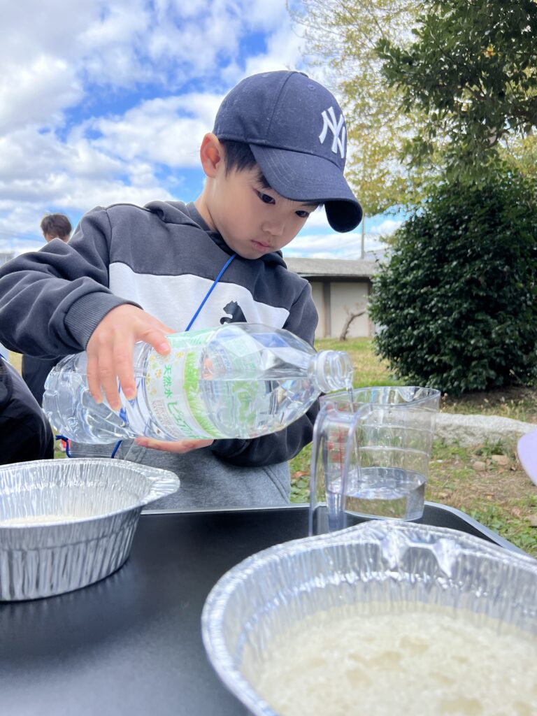 【年中〜小6対象】四日市市・菰野町で人気のキッズスポーツ。MiRAIのキャンプで、子どもが集中力を持って慎重にお米の水加減を測る様子。