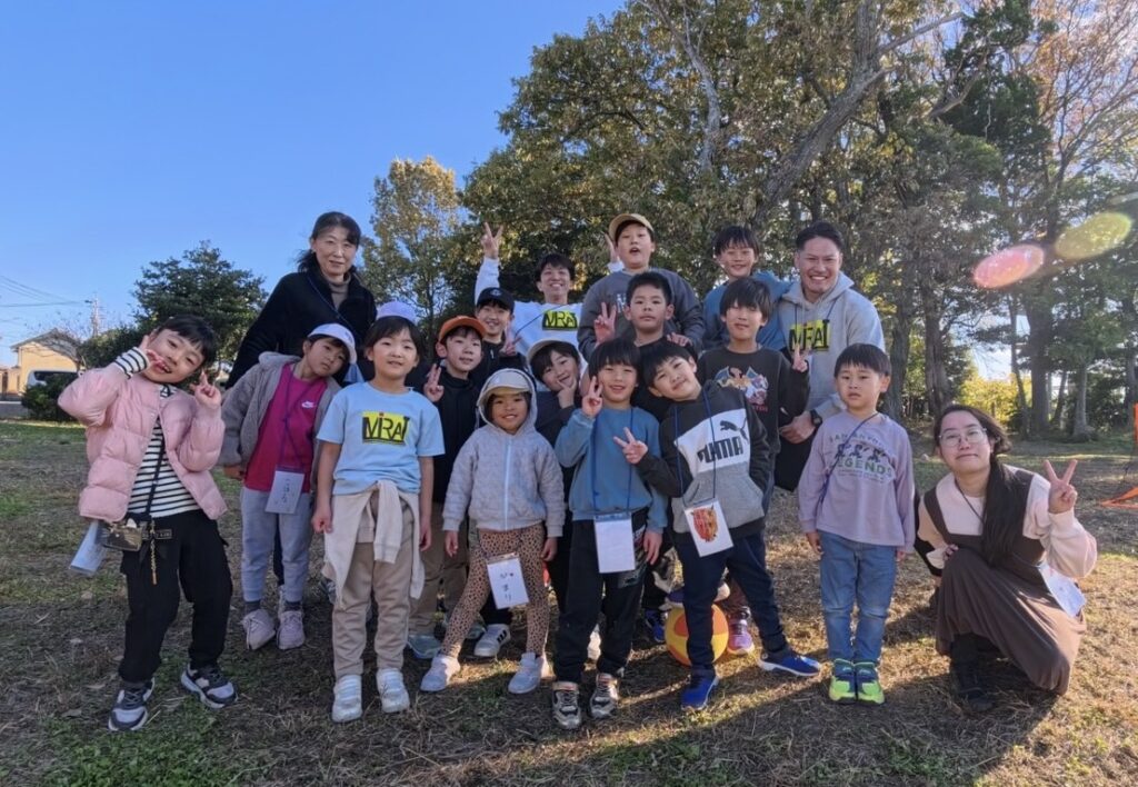【年中〜小6対象】三重県北勢（四日市市・菰野町）の習い事。総合スポーツスクールMiRAIの野外体験に安心して参加した子どもたちと先生の笑顔の集合写真。