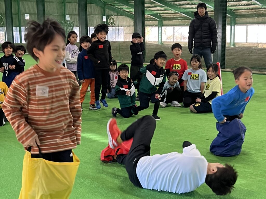 四日市・菰野町の総合スポーツスクールMiRAIの冬の運動会で、年中〜小学生の子どもたちが先生の全力プレーに大笑いしながら障害物競走を楽しんでいる様子