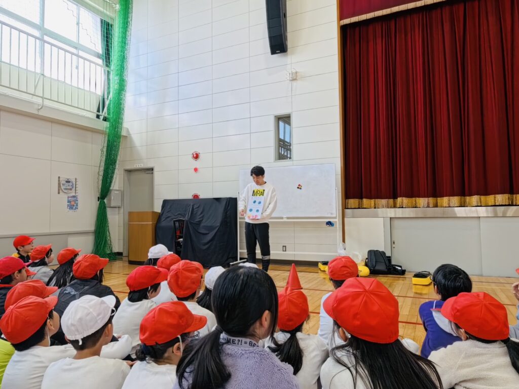四日市市立八郷西小学校の体育館で、けいた先生の説明を興味を持って聞く児童たちの様子（出前授業・体育活動）