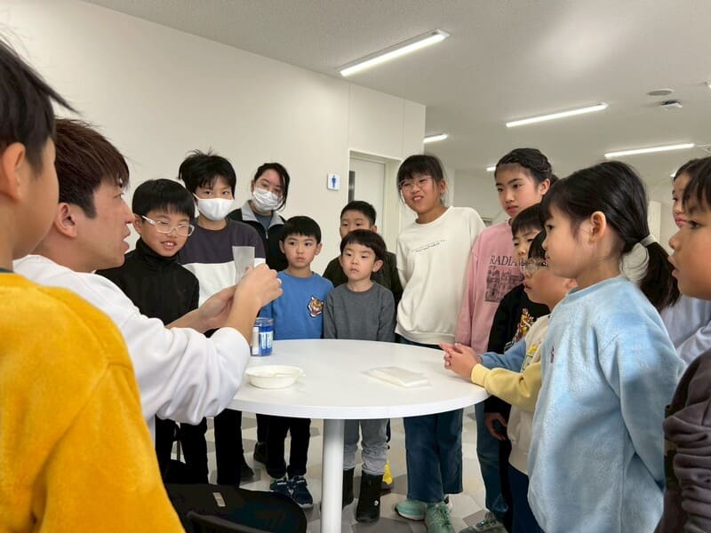 総合スポーツスクールMiRAIの科学教室で、化学反応について説明する先生の話を真剣に聞く子どもたち